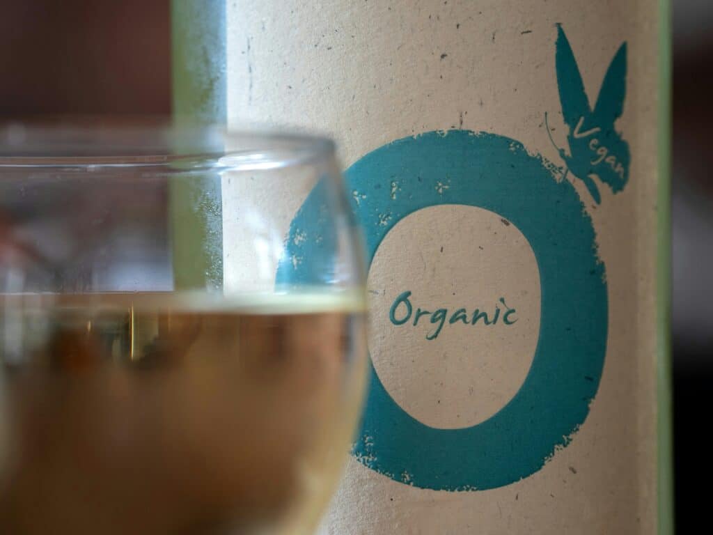 Photo d'un verre de vin avec en fond la bouteille sur laquelle est inscrit le mot organic, bio en anglais. 